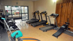 A gym with treadmills, an elliptical, and a bench. - Koltol Guest House (Ibadan)