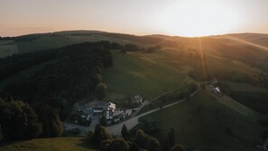 Luftaufnahme einer ländlichen Landschaft mit sanften Hügeln, einer Straße und einigen Gebäuden.
