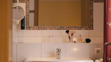 Un baño con lavamanos blanco, un espejo y un salpicadero de azulejos.
