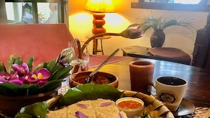 Una mesa de comedor con una cesta de comida, una taza de café y una lámpara al fondo.