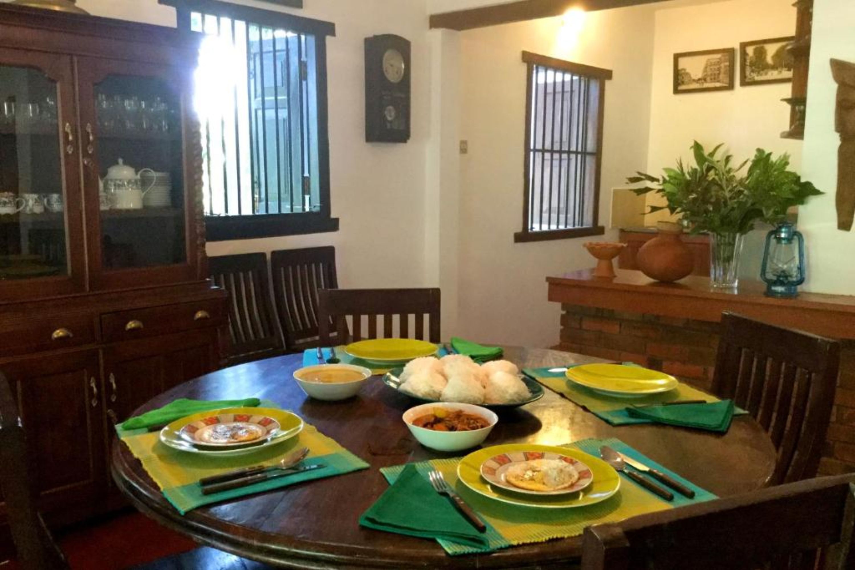 A dining area with a round table set for a meal, surrounded by chairs.