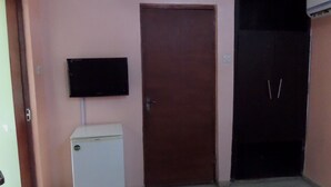 Una stanza con una porta chiusa, un frigorifero bianco e un televisore a schermo piatto montato a parete.