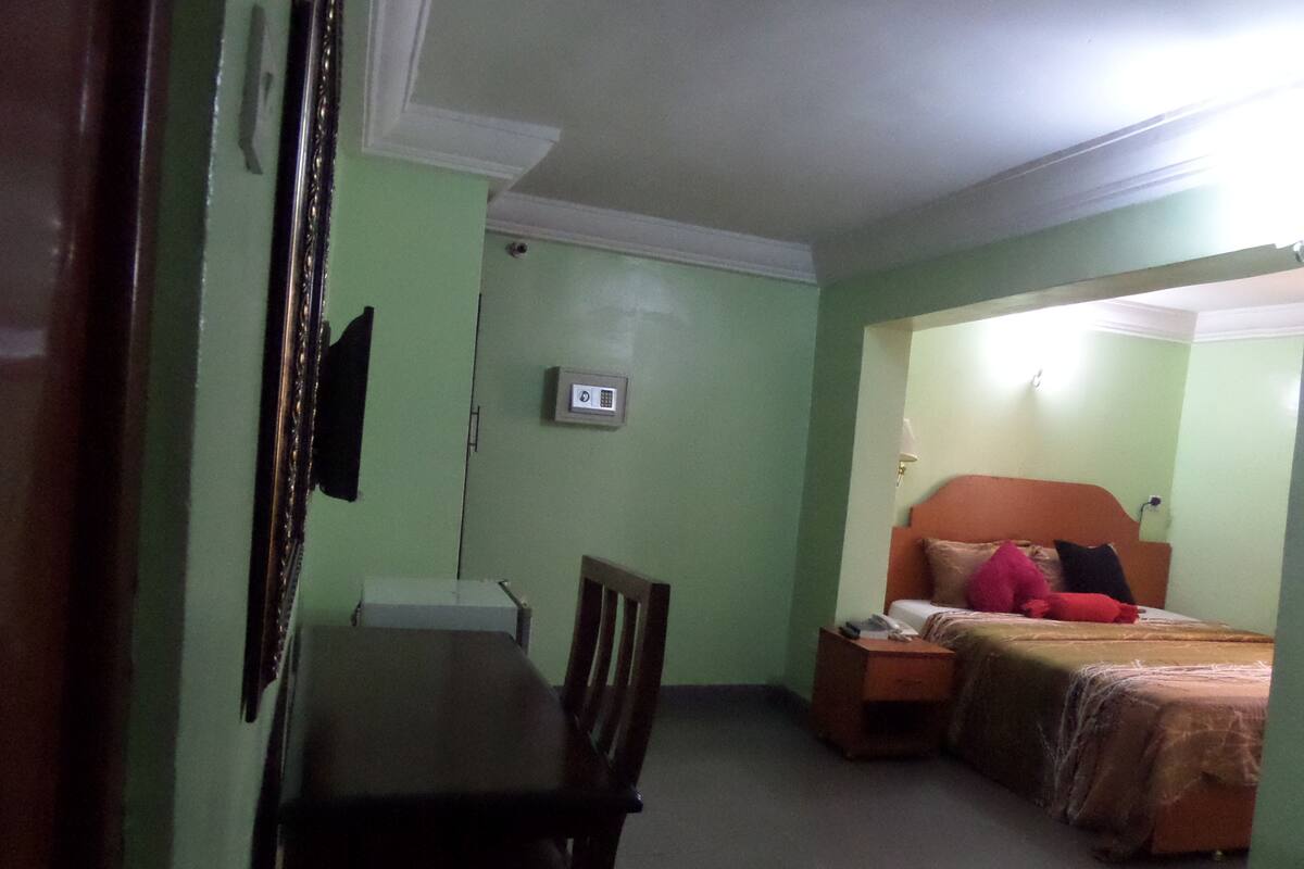 A room with a bed, bedside table, and a desk with a chair.