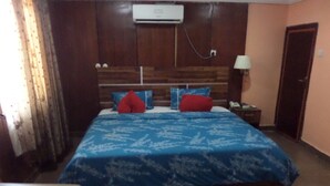 Una camera da letto con una testiera in legno, una coperta blu e un comodino con una lampada.