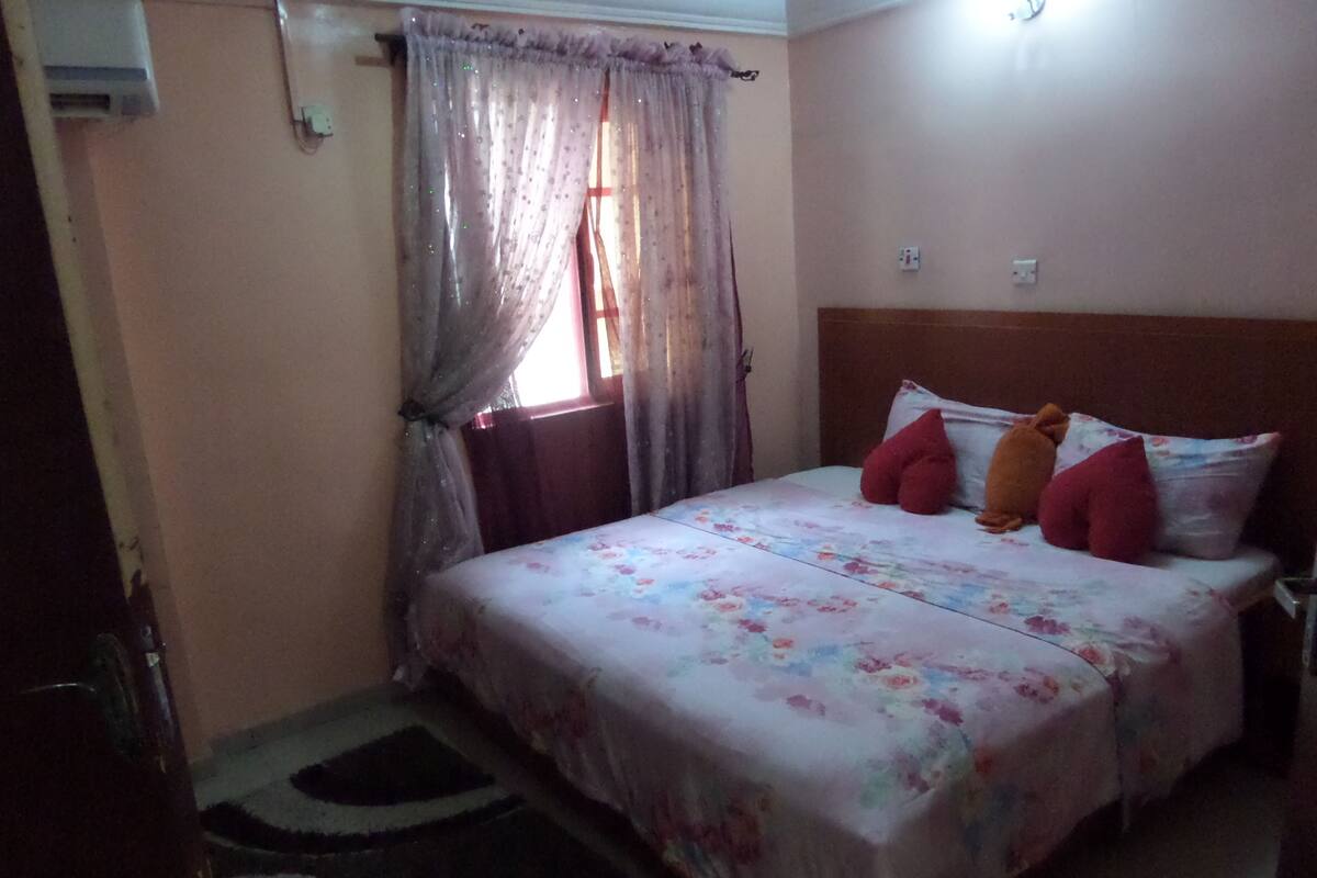 A bedroom with a bed, curtains, a headboard, and a rug.