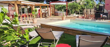 A poolside area with lounge chairs, a hot tub, and a pergola.