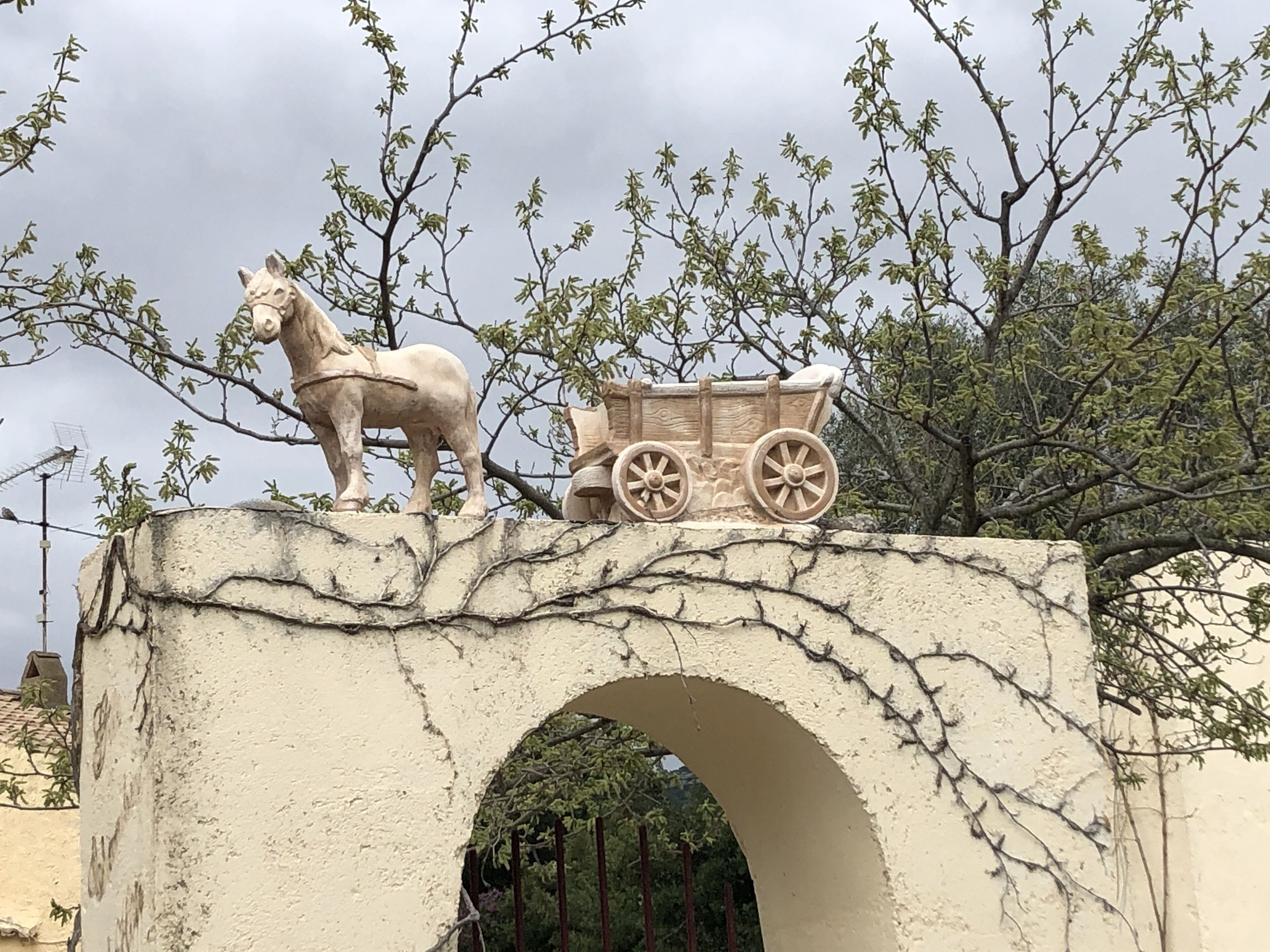A stone bridge with a donkey statue and a wooden cart.