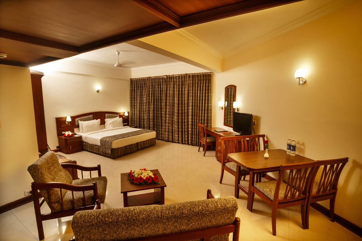 A hotel room with a bed, a desk, a chair, a sofa, and a TV.