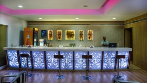 A bar area with a counter, bar stools, and a bartender. - Elite Palazzo (Aluva)