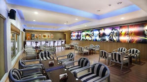 A spacious restaurant with high ceilings, modern lighting, and a vibrant mural on the wall. - Elite Palazzo (Aluva)
