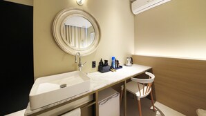 A modern bathroom with a large mirror, a sink, and a small table with toiletries. - Hotel yaja wirye (Seongnam)
