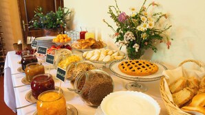 A buffet table with various food items, including fruits, pastries, and condiments.