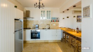 Una cocina moderna con armarios blancos, horno empotrado, lavabo y mesa de comedor de madera con sillas.