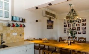 A kitchen with a wooden table, chairs, a sink, and a decorative chandelier.