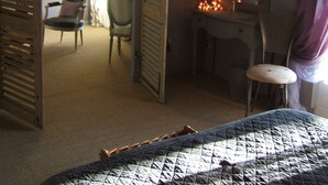 A hotel room with a bed, a desk, a chair, a mirror, and a hanging light fixture. - Chambres d'Hôtes de la Ferrage (La Tour-d'Aigues)