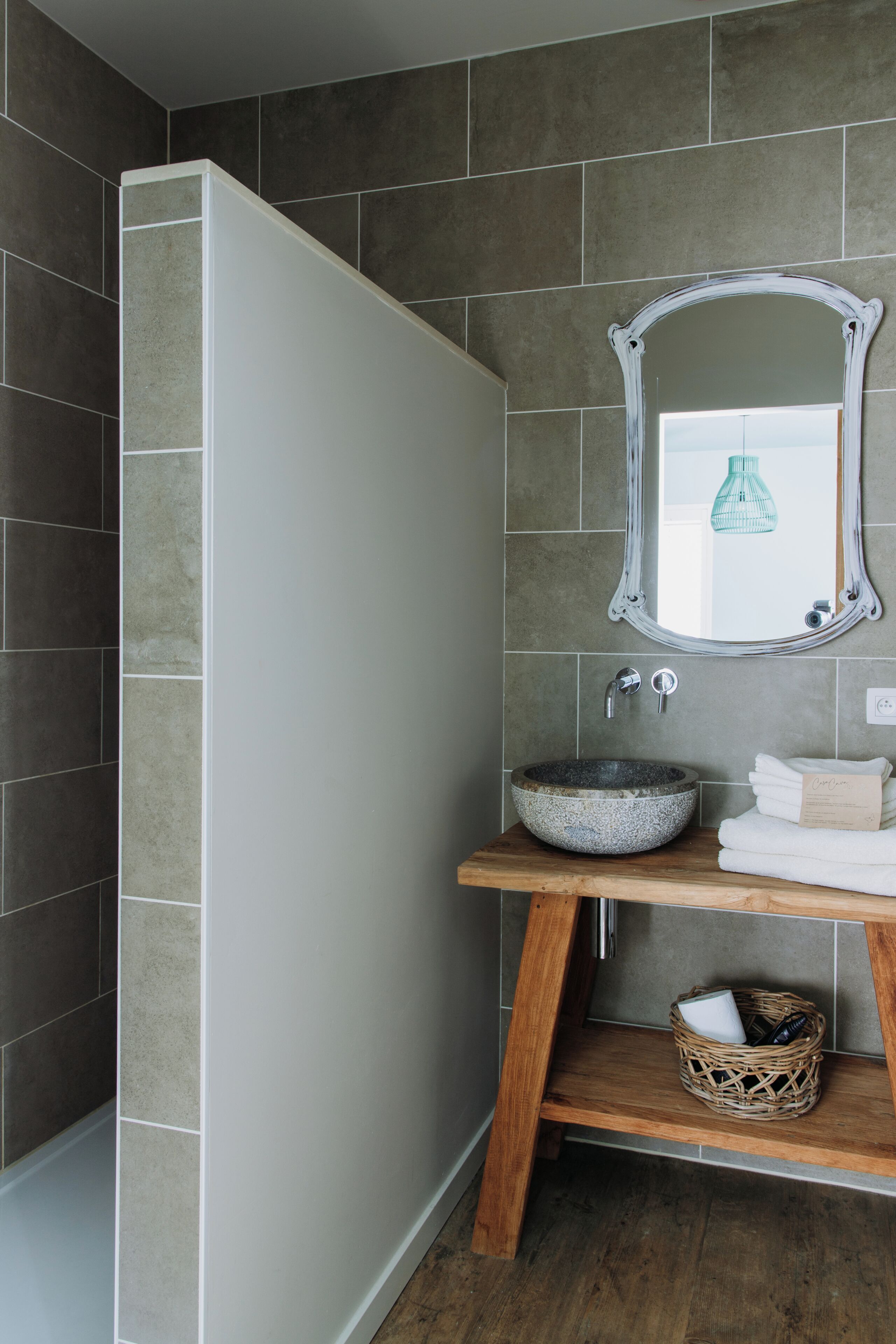Un baño con un espejo grande, un lavabo sobre encimera y un mueble de tocador de madera.