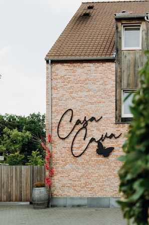 A brick building with a metal gutter and a wooden door. - B&B Casa Cava (Dendermonde)