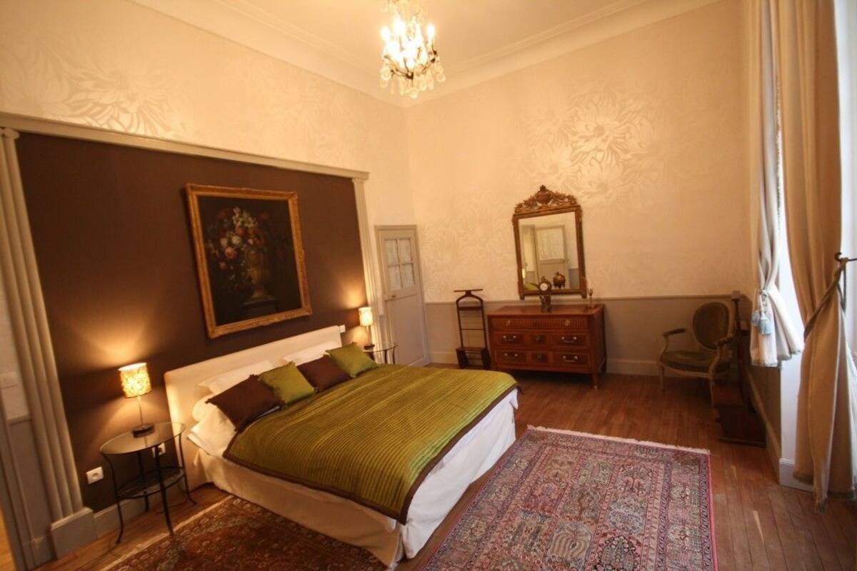 Een slaapkamer met een groot bed, een kaptafel, een spiegel en een kroonluchter.