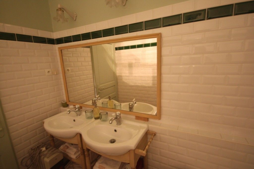 Un baño con dos lavamanos, un espejo y un perchero para toallas.