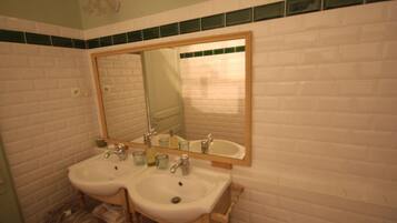 Un baño con dos lavamanos, un espejo y un perchero para toallas.