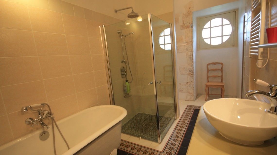 Une salle de bain avec une douche à parois de verre, une baignoire sur pieds et un lavabo.