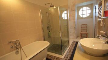 Une salle de bain avec une douche à parois de verre, une baignoire sur pieds et un lavabo.
