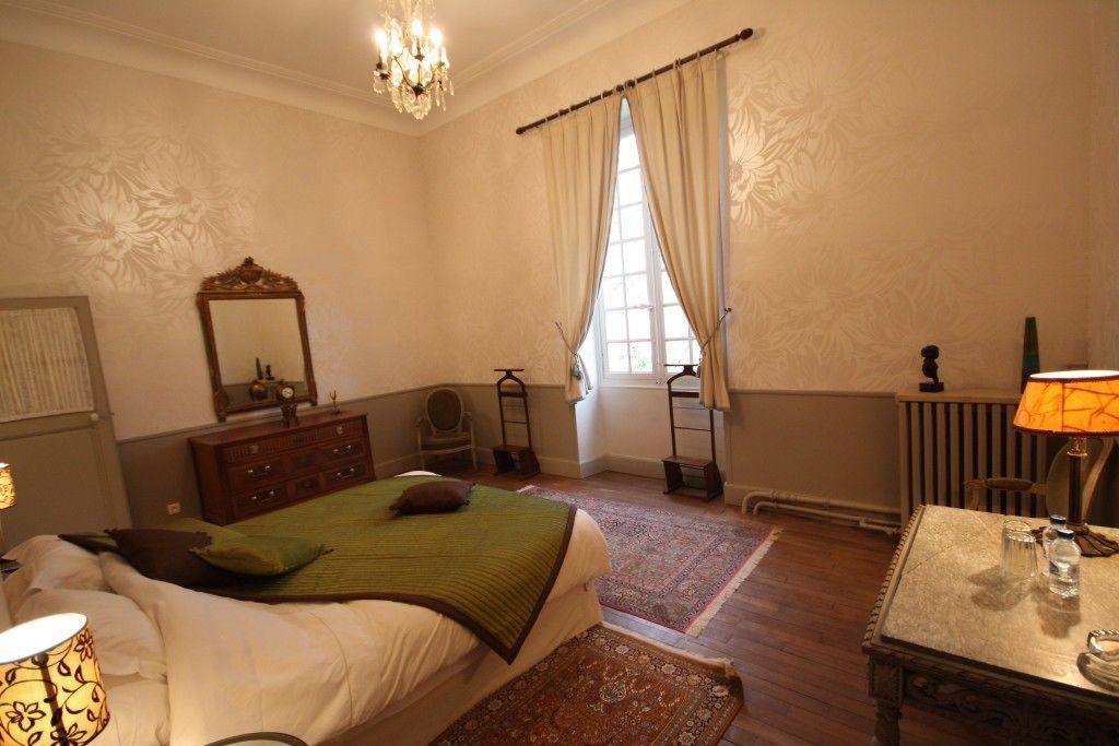 Un dormitorio con cama, cómoda, espejo, candelabro y una mesa con lámpara.