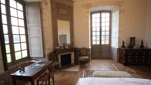 Une pièce avec une cheminée, un bureau, une chaise, un lit et une commode.