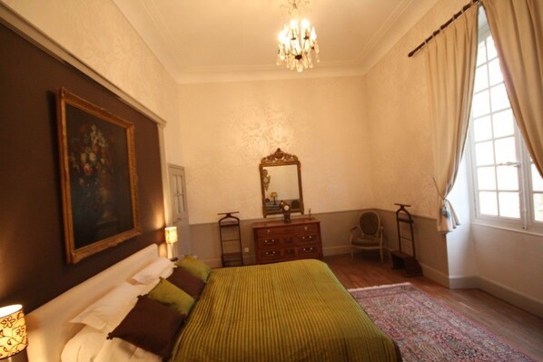 A bedroom with a bed, dresser, mirror, and a painting on the wall.