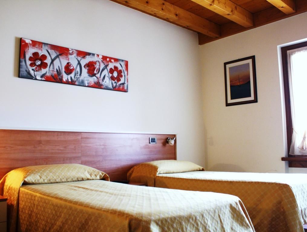 Ein Zimmer mit zwei Betten, einem Holzkopfende, einem Gemälde und einem gerahmten Bild an der Wand.