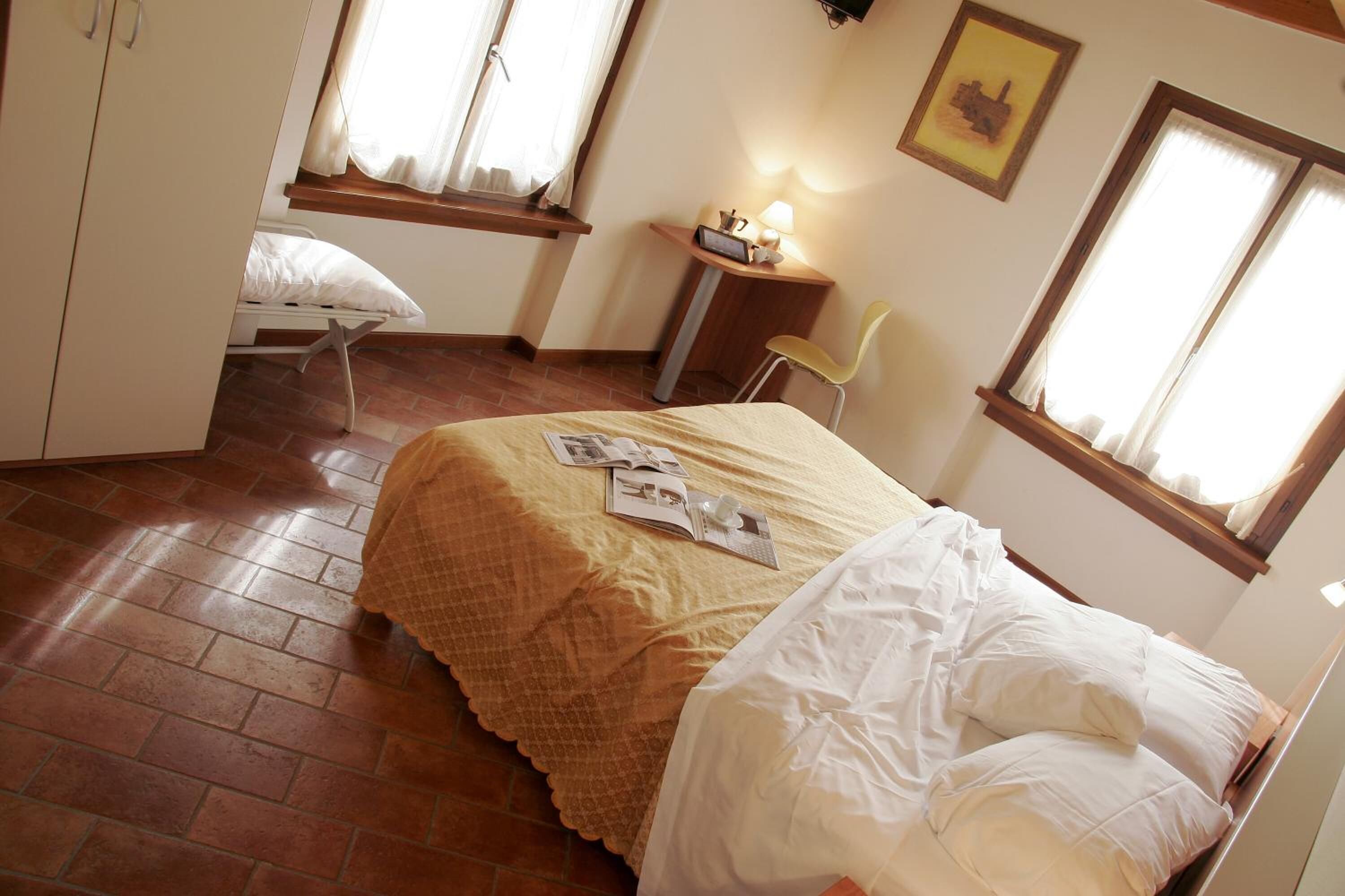 Een slaapkamer met een bed, een bureau, een stoel en een raam.