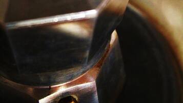 Un primo piano di un oggetto metallico con un pomello e un beccuccio, probabilmente una caffettiera.
