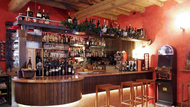 A bar area with wooden stools, a counter with bottles, and a jukebox. - Hotel Bed & Wine (Negrar)