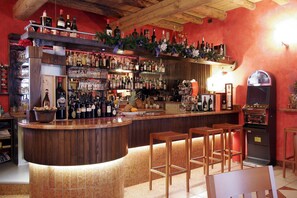 Zona de bar amb tamborets de fusta, una barra plena de botelles i un jukebox.