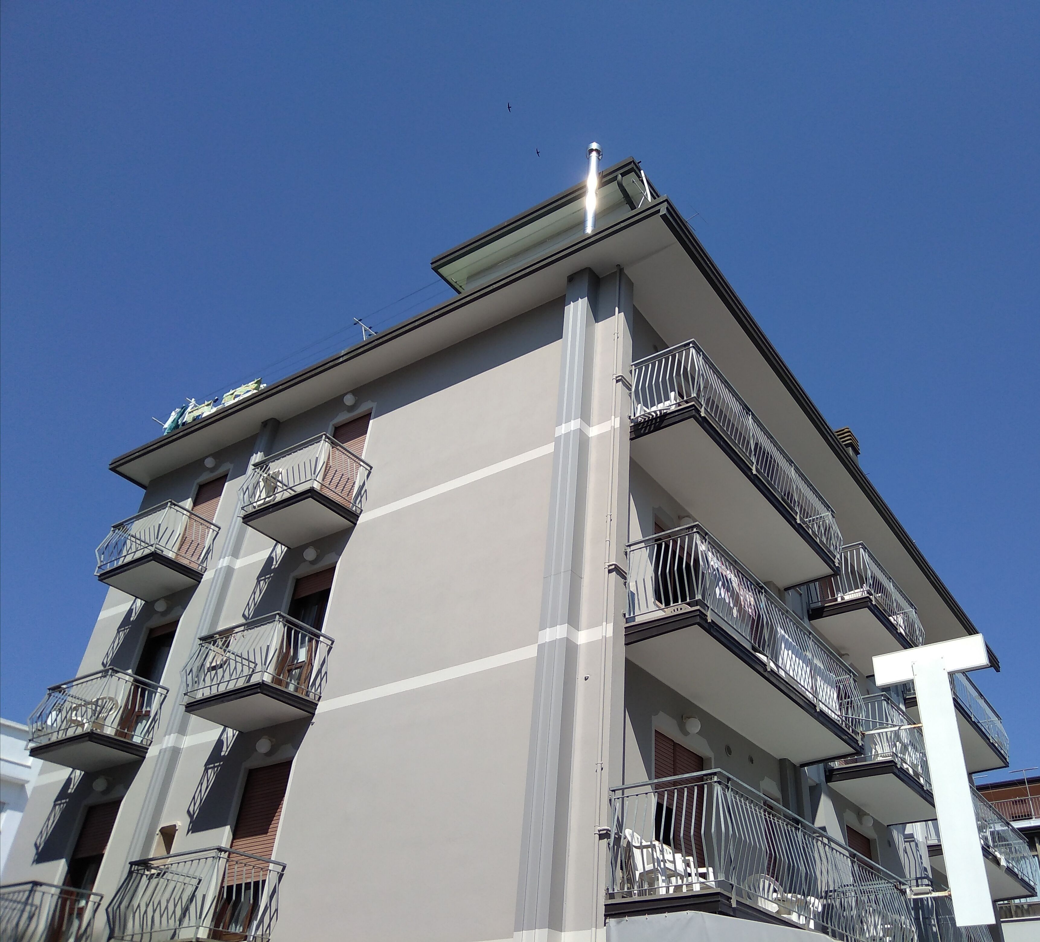 A multi-story building with balconies, a flat roof, and a clear sky.