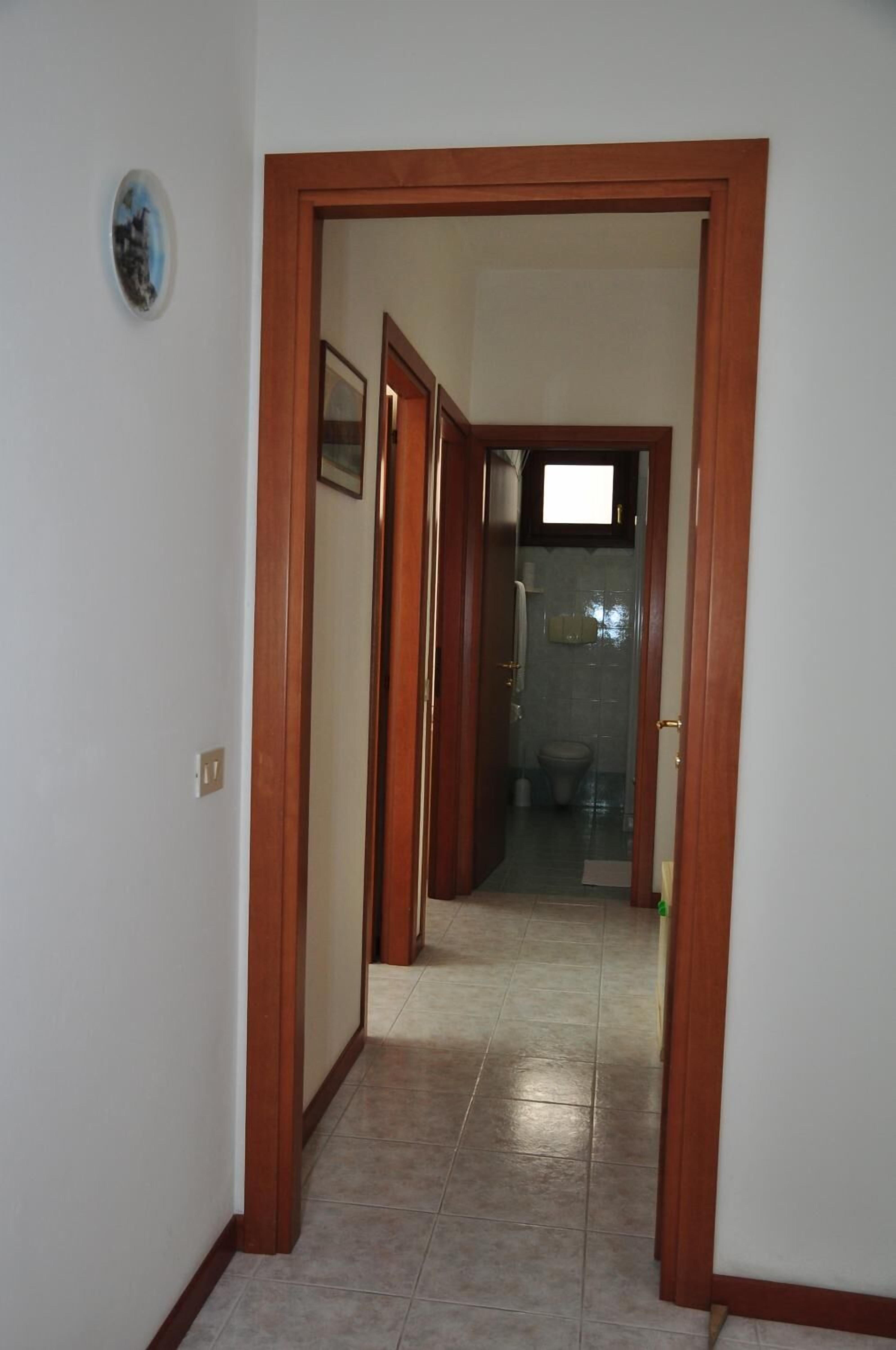 Un couloir avec un cadre de porte en bois menant à une salle de bain.