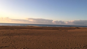 Una playa con formaciones de arena dibujadas y un cielo despejado.