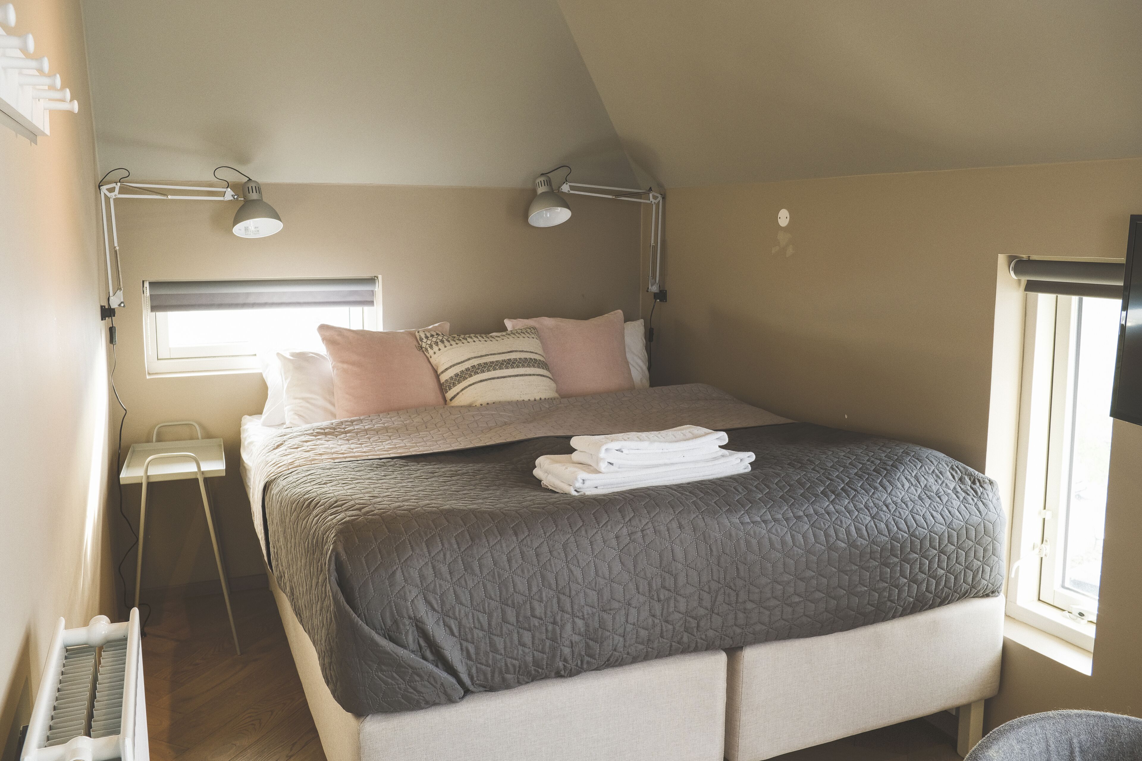 Une chambre à coucher avec un lit, deux lampes de chevet, une fenêtre et un radiateur.
