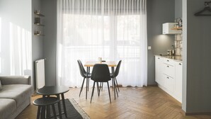 Una sala de estar moderna con comedor, un sofá, una mesita y una cocina con armarios y encimera.
