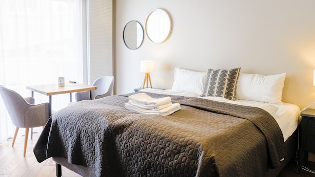 Habitación de hotel con cama, escritorio, silla, lámpara y dos espejos en la pared.