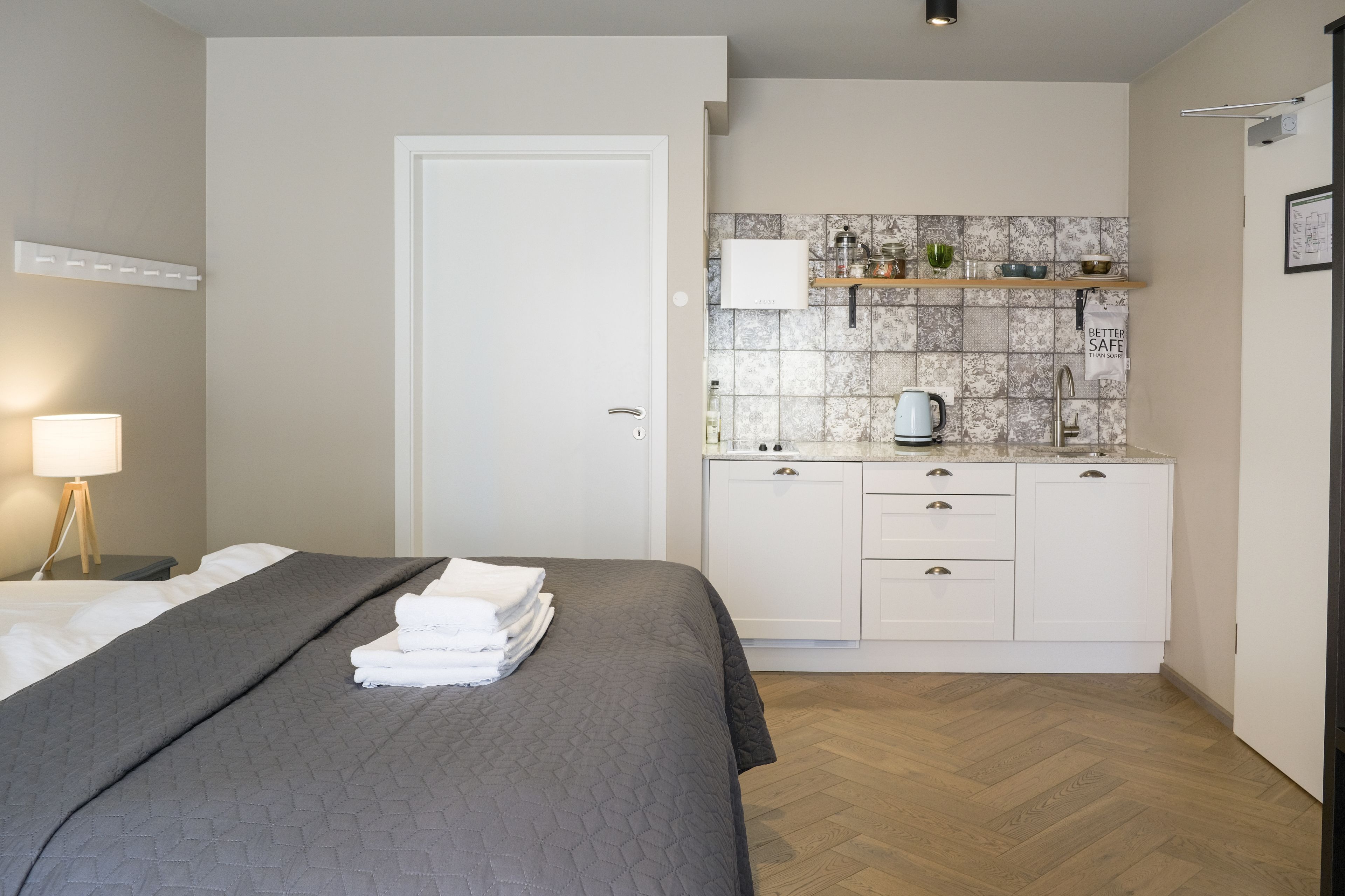 A bedroom with a bed, a bedside table, a lamp, and a neatly made bed with folded towels.
