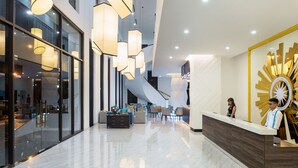 A modern hotel lobby with a reception desk, seating area, and a staircase. - Cross Vibe Viet Tri (Thanh Mieu)