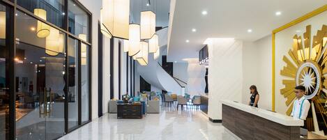 Un moderno vestíbulo de hotel con una recepción, zona de estar y una escalera.