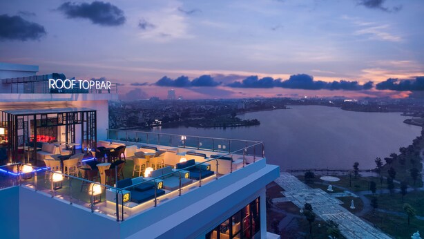 A rooftop bar with seating and a view of a river at dusk. - Cross Vibe Viet Tri (Thanh Mieu)