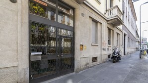 Ein Gebäude mit einem großen Metalltor, einem Motorrad, das am Gehweg geparkt ist, und einem Straßenschild.