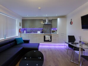 A modern kitchen with a built-in microwave, oven, and stainless steel range hood. - Live in Leeds Greenhill Bungalows (Leeds)