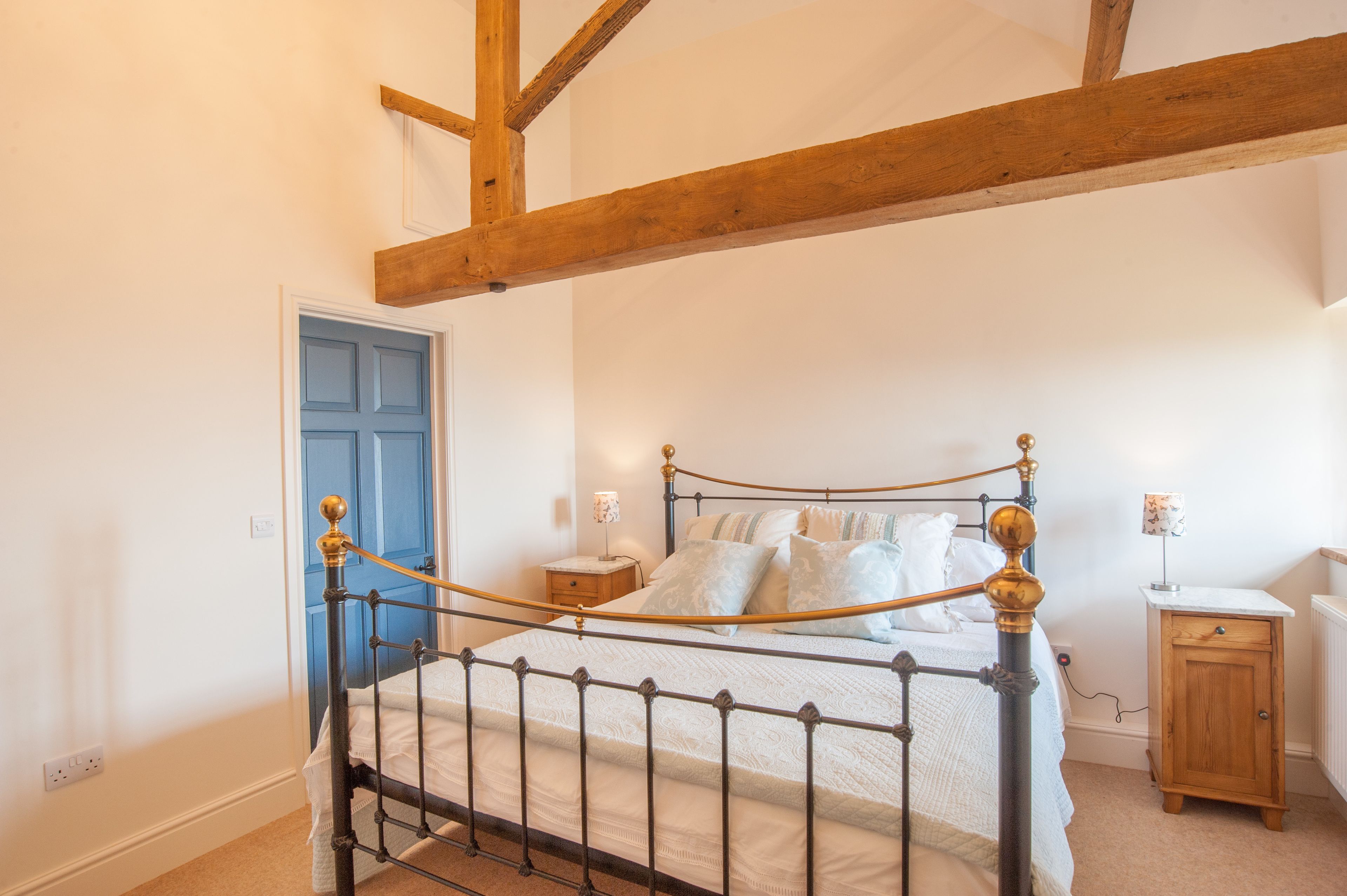 A bedroom with a four-poster bed, a wooden headboard, a bedside table, a nightstand, and a small cabinet.