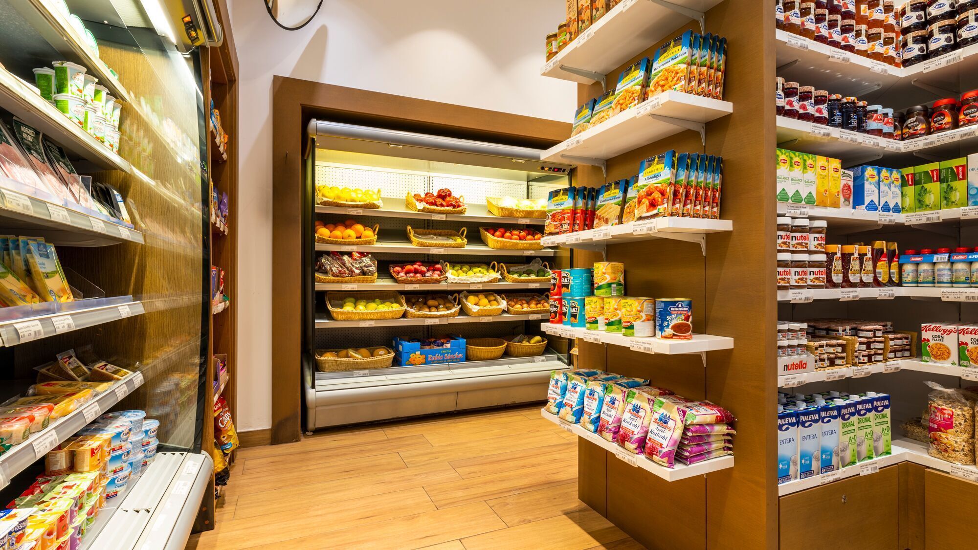 Een supermarkt met schappen vol diverse levensmiddelen, waaronder fruit, groenten en houdbare producten.