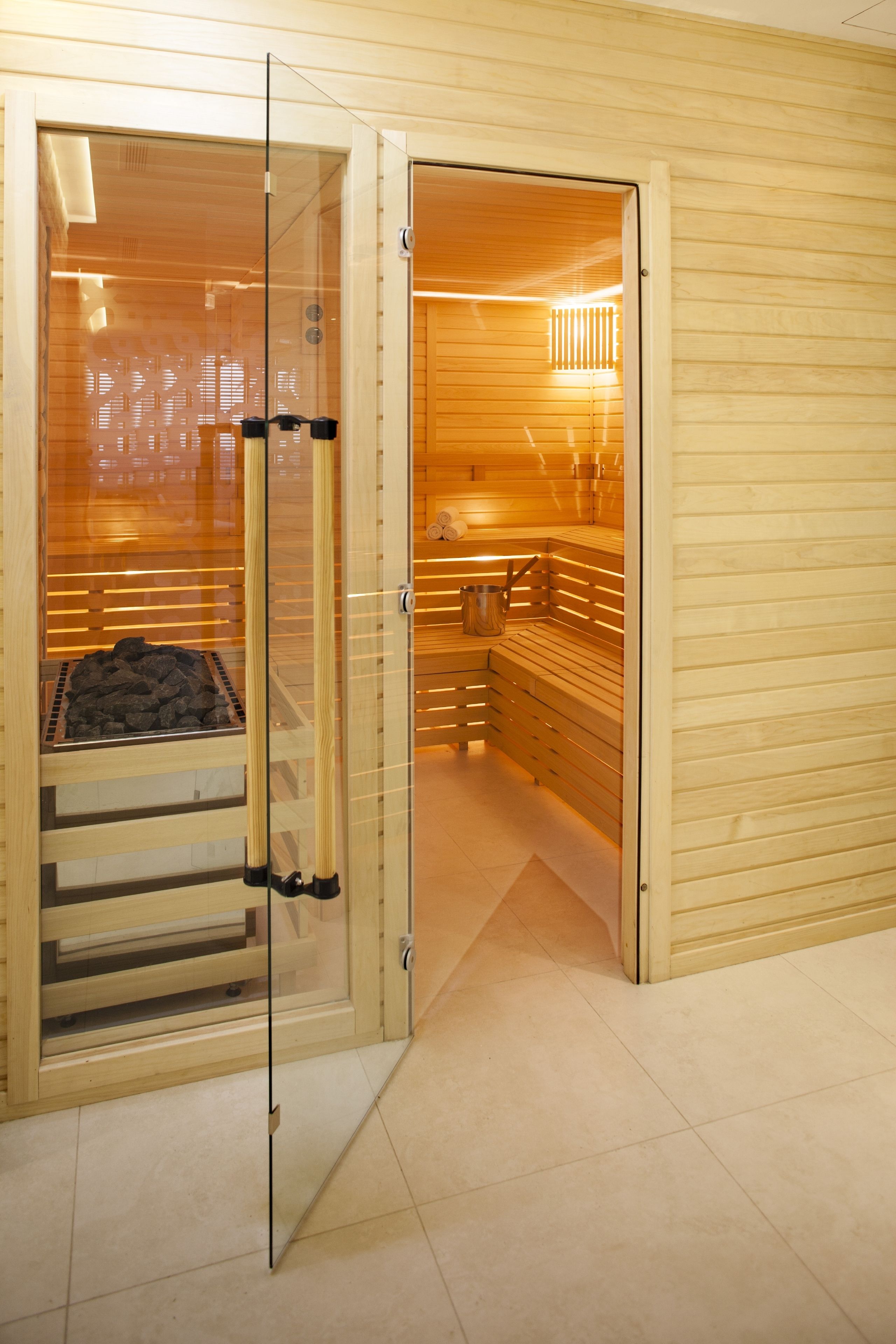 A sauna room with wooden benches and a glass door.