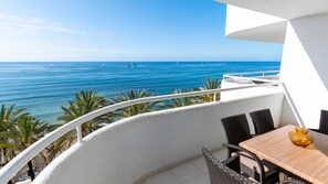 A balcony with a view of the sea, wicker furniture, and a table with a vase. - Hapimag Resort Marbella (Marbella)